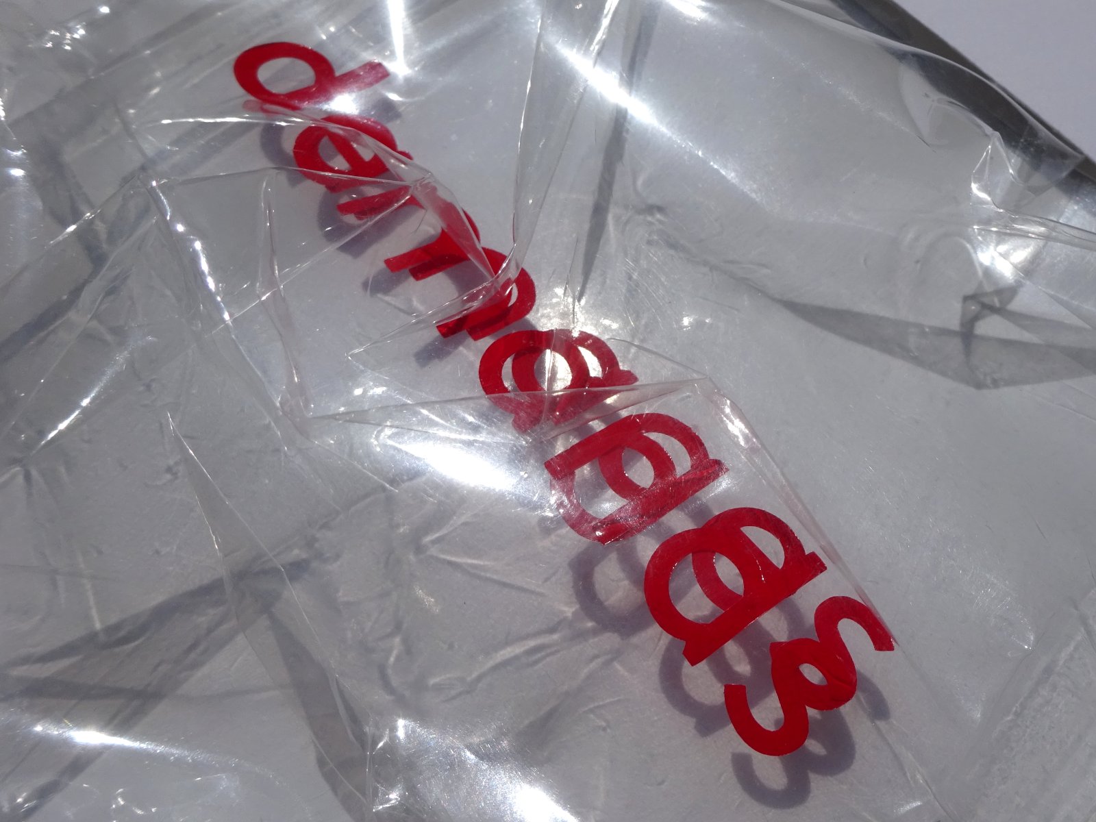 Close-up view. Plastic wrapping is reflecting light. Focus on the letters.